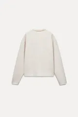 Sweater color crema de tejido suave, con cuello redondo en rib y mangas largas sin costuras.