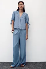 Pantalón celeste de tiro alto con cintura elástica ajustable con cordones, bolsillos delanteros y traseros, y pernera ancha.