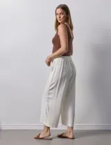 Pantalón de lino color crudo, de corte ancho y tiro alto, con bolsillos laterales y cintura elástica.