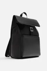 Mochila negra de cuero sintético, con solapa y cierre magnético. Tiene un compartimento principal con espacio para dispositivos electrónicos de hasta 13 pulgadas y un bolsillo con cierre. En la parte frontal cuenta con un bolsillo con cierre. Tiene asa de mano y dos asas de hombro ajustables y acolchadas.