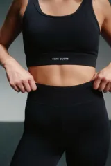 Calza deportiva negra, tiro alto, corte 7/8 y paneles de mesh en la parte inferior de la pierna.