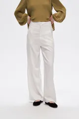 Pantalón de lino color blanco, de corte ancho y tiro alto, con bolsillos laterales y pinzas.