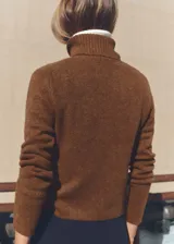 Sweater color beige de tejido de punto con cuello alto y mangas largas.