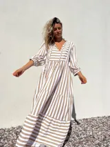 Vestido largo tipo túnica con rayas verticales color beige y crudo, escote en V con lazos y mangas 3/4.