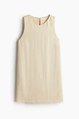 Vestido corto sin mangas color beige. Modelo levemente evasé con escote redondo, abertura de cerradura con botón oculto en la nuca y bajo recto. Parcialmente forrado.