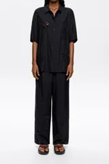 Pantalón negro de corte recto con largo tobillero, bolsillos diagonales delanteros, cintura elástica trasera y bordado inglés en el bajo de la pierna.