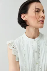 Camisa sin mangas color verde agua con cuello mao, cierre frontal con botones y detalle de puntilla en los hombros.