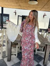 Vestido largo de fibrana y viscosa con estampado paisley en tonos rojos y negros. Tiene mangas cortas con punto smock en la espalda y escote en V.