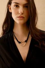 Collar con cordón negro trenzado y dije de corazón dorado.