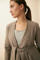 Chaqueta corta color beige, entallada, con escote en V, manga larga y cierre frontal con lazo fijo. Confeccionada en lana fina sin teñir, con bolsillos escondidos y terminaciones enviadas. Hecha 100% en Uruguay.