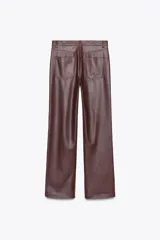 Pantalón negro de tiro medio, con trabillas en la cintura, cinco bolsillos y pernera ancha. Cierre frontal con cremallera, botón oculto y gancho metálico.