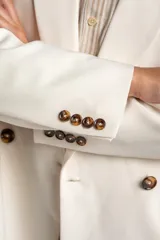 Blazer color crema, de corte oversize, con solapas de muesca, cierre con doble botón y bolsillos laterales con solapa.