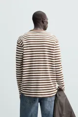Remera de manga larga a rayas horizontales marrones y blancas, de corte recto y cuello redondo.