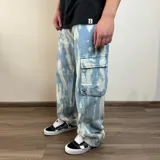 Pantalón jean cargo celeste con efecto tie-dye, corte holgado y bolsillos laterales.