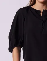 Blusa blanca de gasa marca Sioni, con cuello a la base y escote en V con botones.