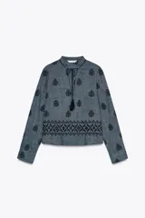 Blusa azul con bordados negros, cuello redondo con escote en pico y cordones ajustables terminados en borlas.