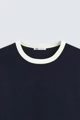 Camiseta azul marino de corte regular, cuello redondo y manga corta con ribete blanco en cuello y mangas.