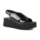 Sandalias negras de charol con plataforma y tiras cruzadas.