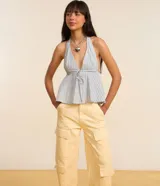 Blusa peplum con escote halter y lazo en el frente, con patrón de rayas verticales azules y blancas.