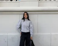 Campera entallada de bengalina color celeste, con cierre frontal, cuello subido, bolsillos delanteros y mangas acampanadas con botones a presión en los puños.