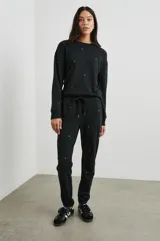 Pantalón de jogging negro con estrellas doradas estampadas, cintura elástica con cordón ajustable y puños elásticos.