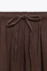 Pantalón bombacho color marrón confeccionado en algodón 100%. Tiro medio con cintura elástica ajustable con cordones y bajo abullonado con elástico.