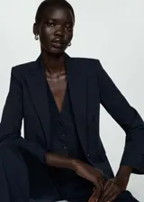 Blazer azul marino con cuello de pico con solapa, hombros estructurados, detalle de pinzas, solapas con muesca, diseño recto y entallado, dos bolsillos de ribete en la parte delantera y abertura posterior.