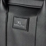 Cartera tipo baúl color negro, de cuero sintético, con doble asa corta y correa larga regulable y desmontable. Tiene cierre superior, dos compartimentos internos y tres bolsillos internos, uno con cierre.