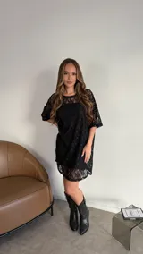 Vestido corto tipo remerón de encaje negro con mangas cortas.