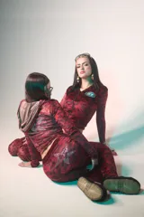 Conjunto deportivo de terciopelo con estampado animal print en tonos rojo y negro. Incluye campera con cierre y capucha, y pantalón acampanado.