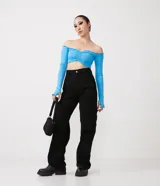 Blusa cropped de media malla color celeste, con escote hombro a hombro, mangas largas con abertura para los dedos y volantes en el escote, puños y bajo.