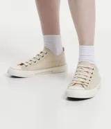 Championes bajos de lona color beige, con puntera redonda, cierre con cordones y suela de goma blanca con detalle de línea en relieve.