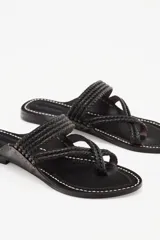 Sandalias negras de cuero con tiras trenzadas y suela plana.