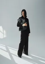 Pantalón negro de vestir, de corte recto y largo, con tiro medio, trabillas, bolsillos laterales y cierre frontal oculto con botón, gancho y cremallera. Incluye lazo ajustable en la cintura y forro interior.