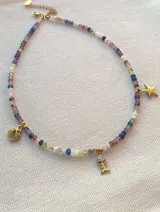 Collar corto de acero dorado con cuentas de piedras naturales multicolores y dijes colgantes de estrella de mar, ostra y esqueleto de pez.