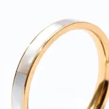 Anillo de acero con diseño nacarado en tonos blanco y dorado.