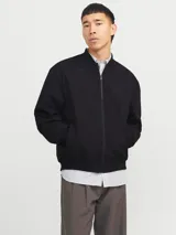 Campera bomber negra de manga larga con cuello baseball y fit cómodo. Diseño con cierre frontal de cremallera, bolsillos delanteros funcionales y puños de canalé.