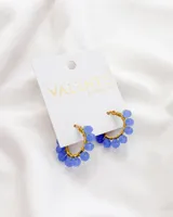 Aros de acero dorados, tipo argolla, con cuentas de cristal facetado color azul.