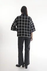 Sweater color crema con cuello alto y mangas cortas anchas, con diseño de cuadros negros.