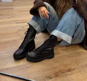 Botas de cuero negras con cordones, suela track y cierre lateral.