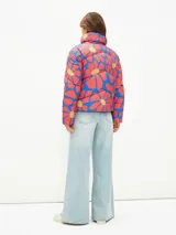 Campera puffer corta con estampado abstracto en tonos verde, naranja y azul. Tiene cuello alto, cierre frontal con cremallera y bolsillos laterales.