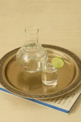 Jarra de vidrio transparente con diseño de estrellas doradas. Incluye un vaso de vidrio transparente con diseño de líneas verticales doradas.