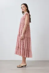 Maxi vestido de corte imperio, color rosa con estampado floral liberty en tonos fucsia. Tiene escote en V, mangas cortas con volados y falda larga con volantes. Cierre frontal con botones.