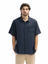 Camisa negra de manga corta con cuello clásico, cierre frontal con botones y bolsillo de parche en el pecho.