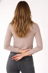 Remera de manga larga entallada en color blanco, confeccionada en algodón. Presenta cuello redondo con una hilera de botones frontales y un pequeño bolsillo en el pecho con detalle de botón.