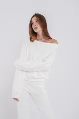 Buzo de felpa blanco, con corte a la cintura y diseño de hombro descubierto con mangas voluminosas.