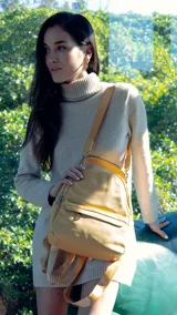 Mochila color mostaza de símil cuero con bolsillo frontal con cierre y broche, apertura superior con cierres metálicos, bolsillos laterales y asa de mano. Incluye bolsillos internos y correas regulables para colgar en la espalda.