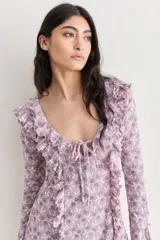 Vestido corto de encaje color lila con estampado floral, escote en V y volados.