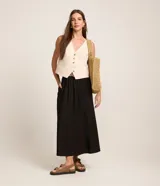 Pollera midi evasé color negro, confeccionada en viscolino, con trabillas en la cintura y cinturón de ráfia con hebilla redonda.