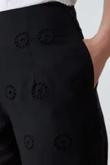 Pantalón negro de corte amplio con bordado de boderie y lazo de ajuste en la cintura.